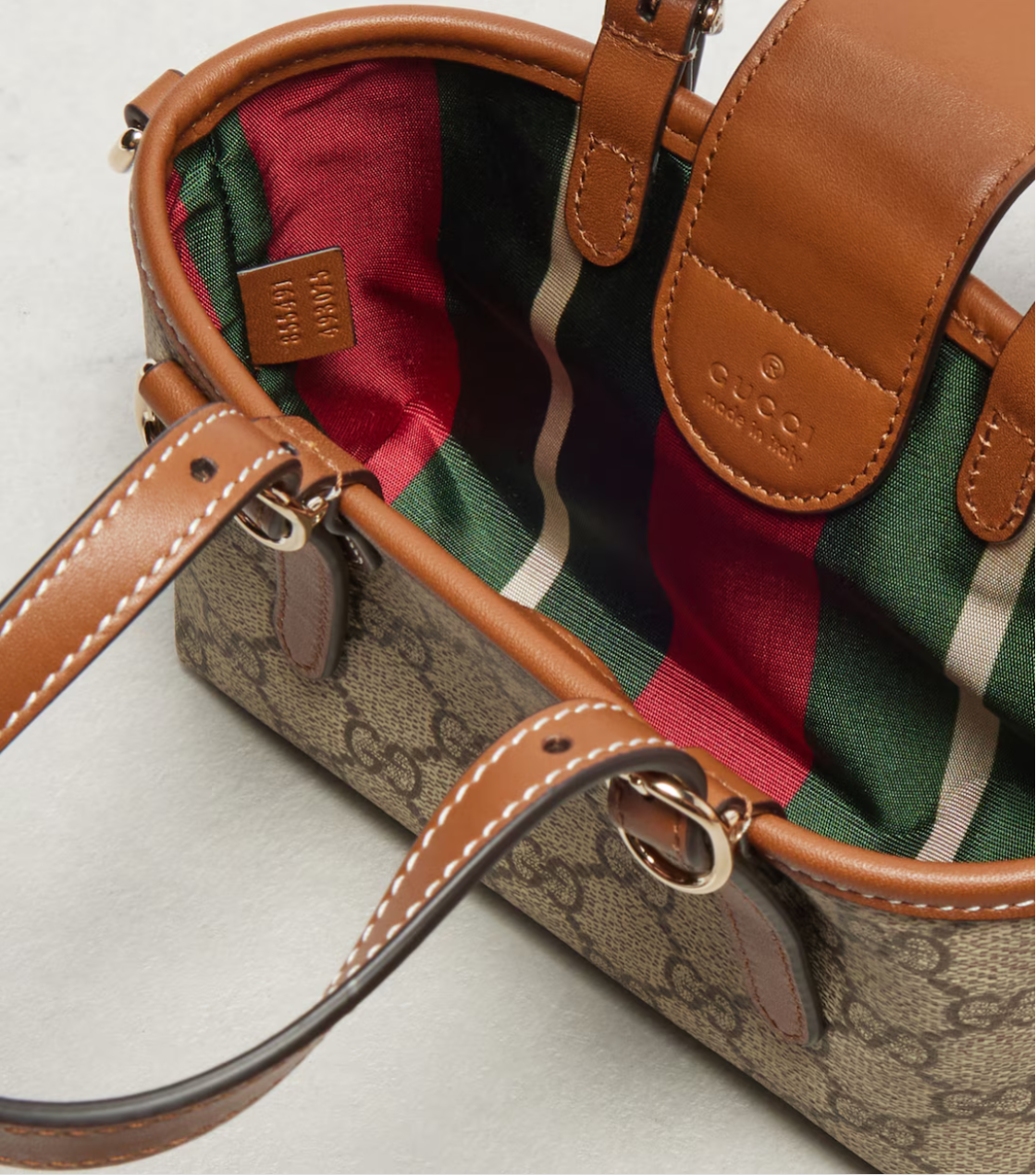 Close-up of a Gucci handbag with plaid lining on a light background