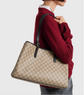Person wearing a red sweater with a beige  gucci handbag featuring a pattern.