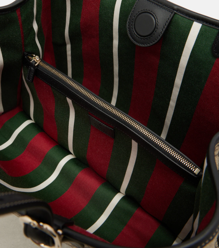 Striped bag with green, red, and white pattern and a black zipper.