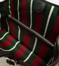 Striped bag with green, red, and white pattern and a black zipper.
