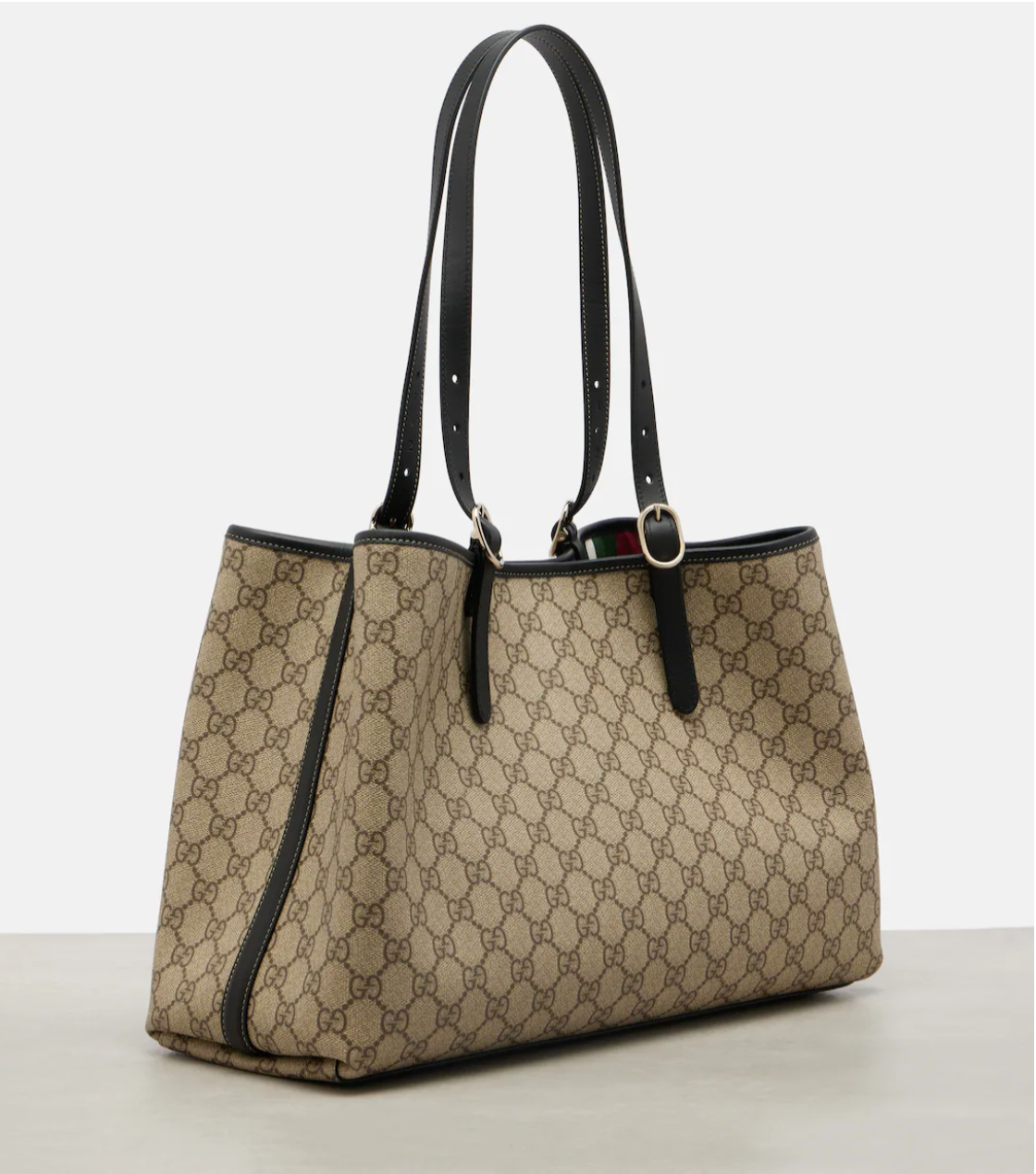 Beige gucci handbag with black accents on a light gray background