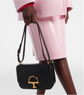 Person holding a black gucci handbag with a gold clasp against a white background
