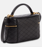 Black quilted handbag with gold accents on a light gray background