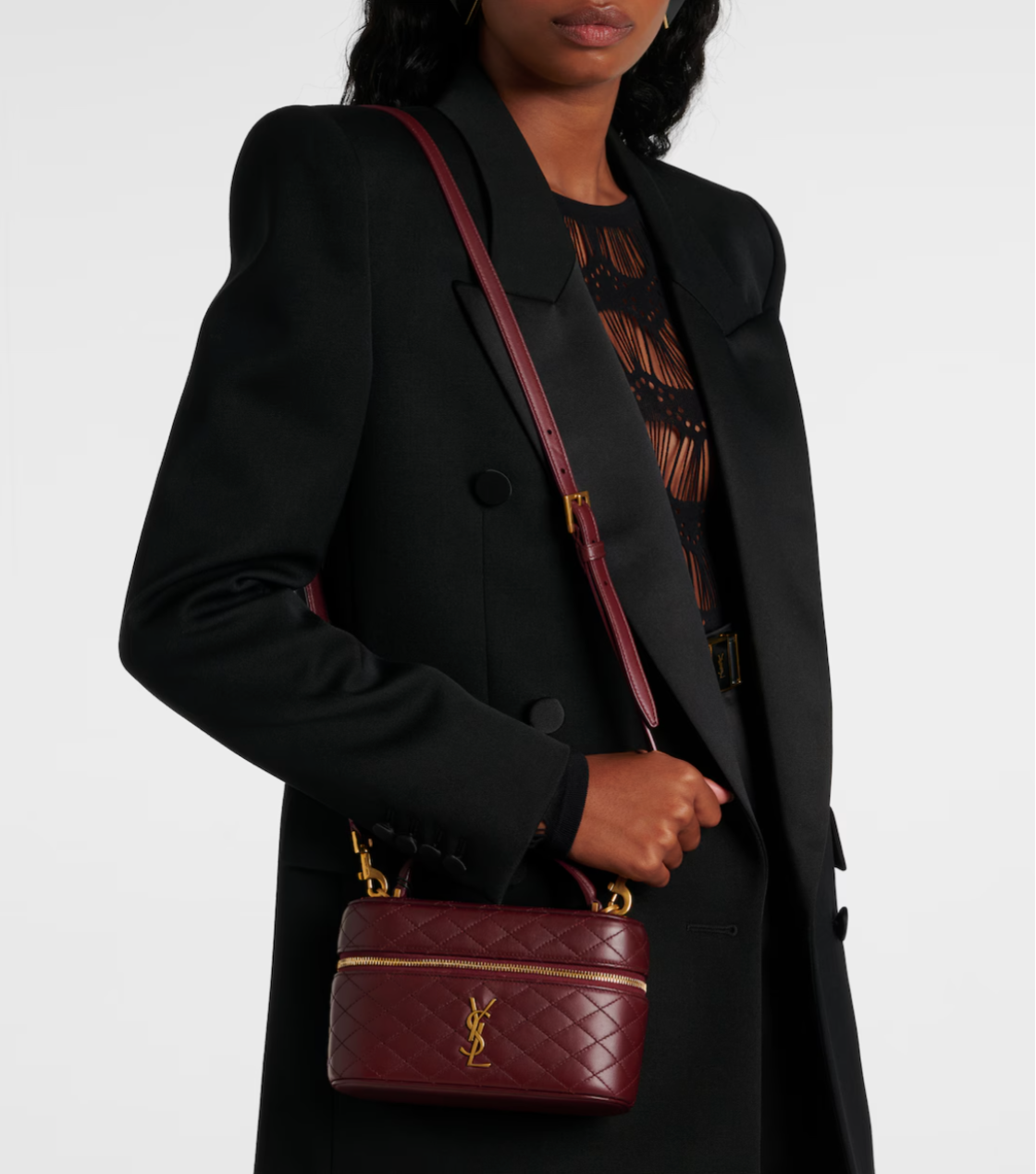 Person holding a maroon handbag with a visible ysl logo against a white background