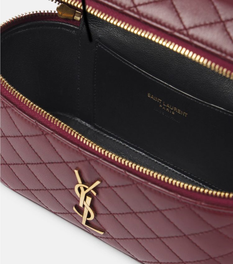 Close-up of a burgundy quilted handbag with gold zipper and logo, featuring Saint Laurent branding.