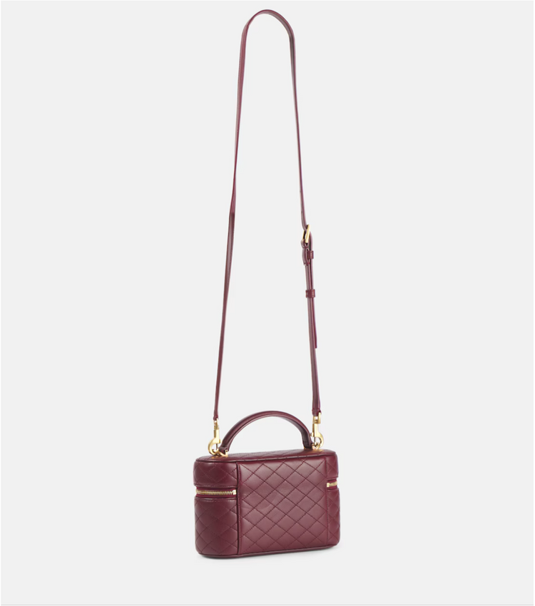 Maroon quilted handbag with a strap on a light gray background