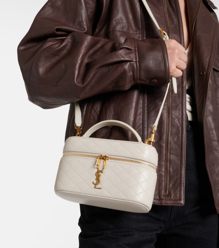 Person holding a white handbag with gold accents against a neutral background