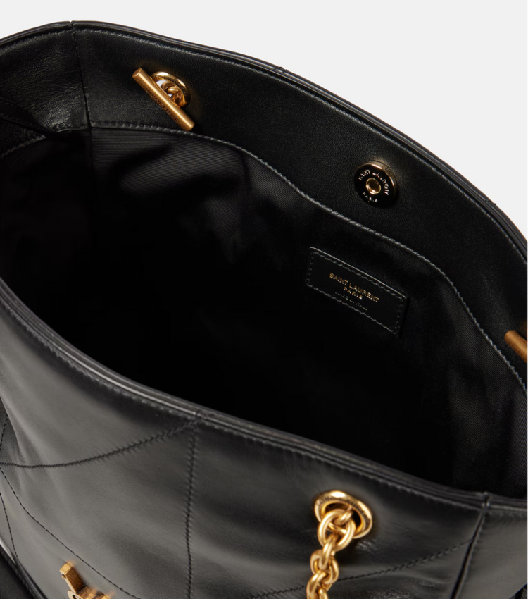 Close-up of a black handbag with gold accents on a white background