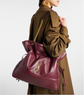 Person wearing a brown coat with a large burgundy handbag featuring a gold chain and YSL logo.