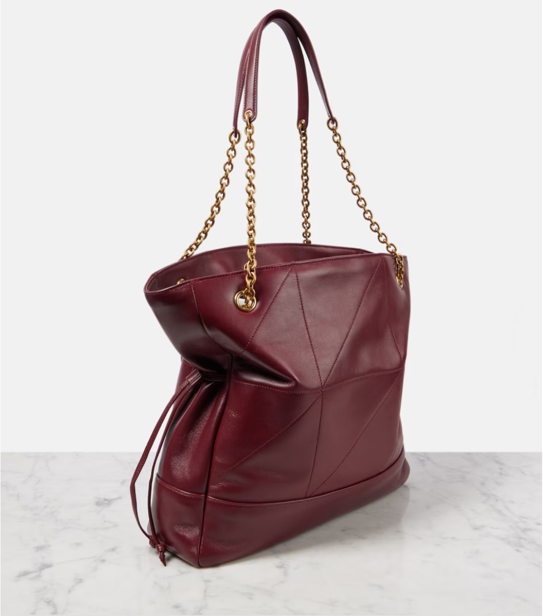 Maroon handbag with gold chain handle on a marble surface