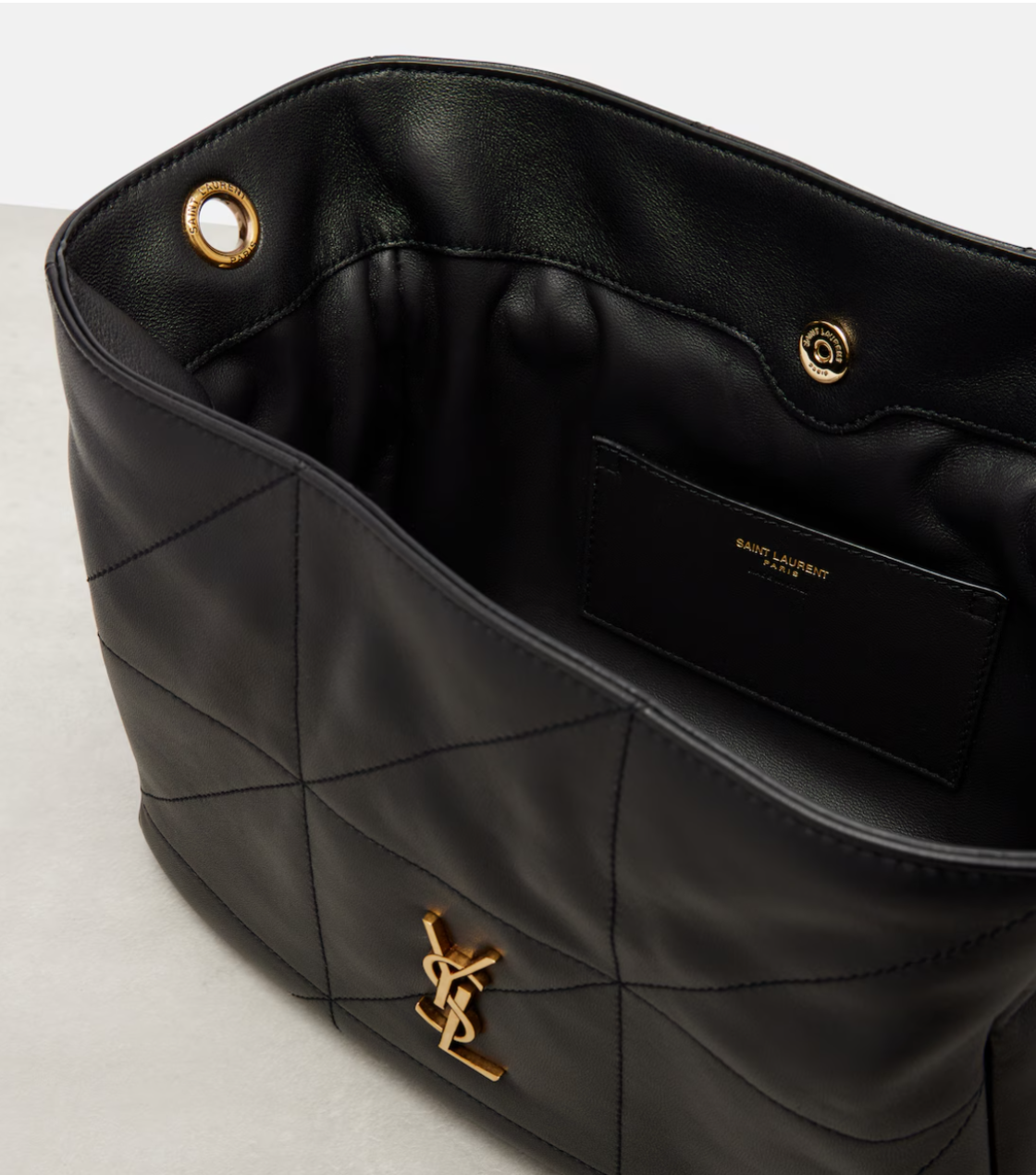 Black quilted handbag with gold YSL logo on a light gray background