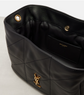 Black quilted handbag with gold YSL logo on a light gray background