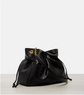 Black leather drawstring YSL bag with gold chain on a light gray background