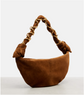 Brown suede handbag with braided handle on a light gray background