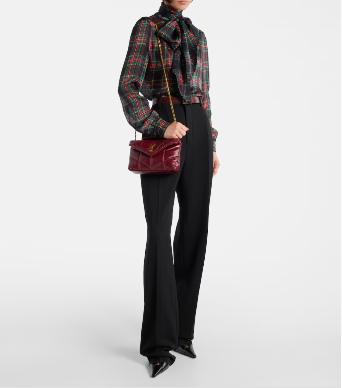 Person wearing a plaid shirt, black pants, and holding a red handbag on a white background