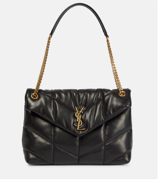 Black quilted handbag with gold chain strap on a light gray background