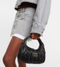Person holding a black Miu Miu handbag against a neutral background