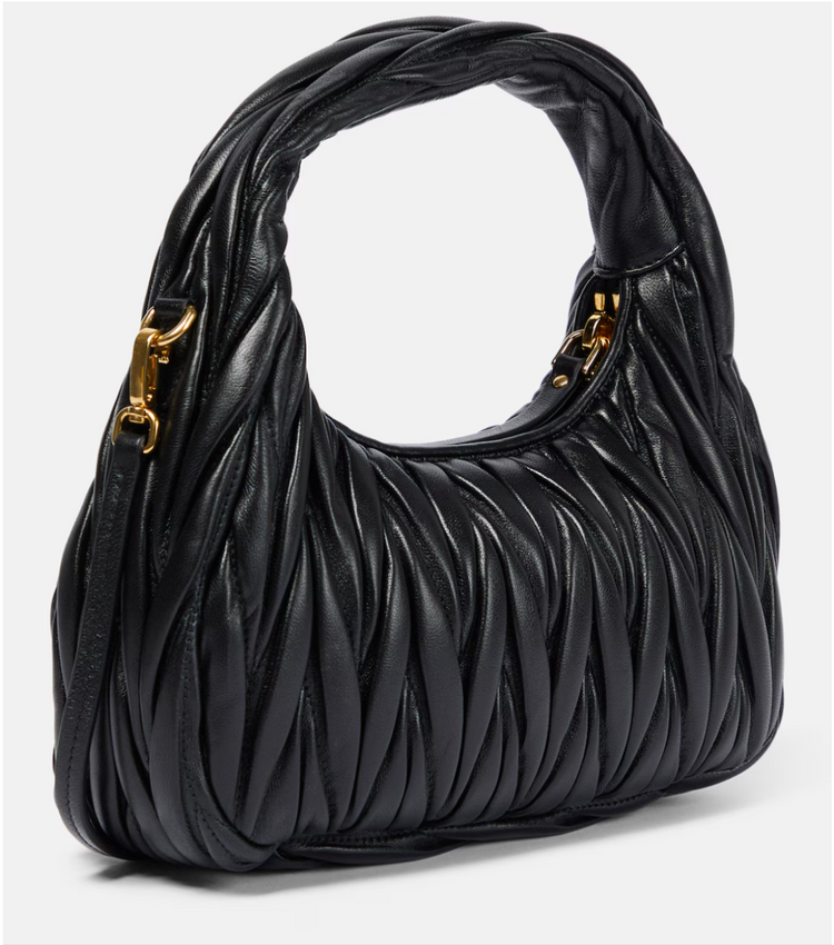 Black quilted handbag with gold hardware on a white background