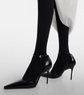 Black high-heeled shoes worn with black tights on a white background