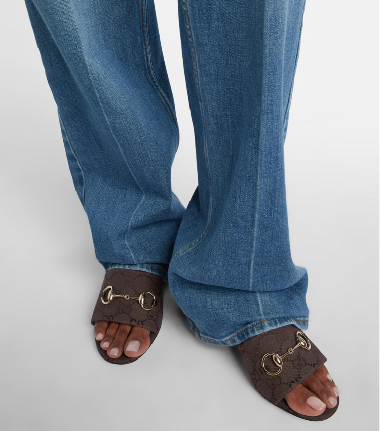 Blue jeans worn with brown sandals on a light gray background