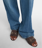 Blue jeans worn with brown sandals on a light gray background