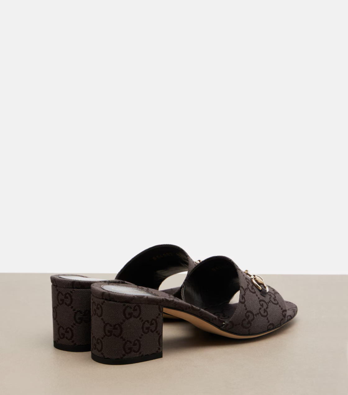 Black Gucci high-heeled shoes on a light gray background