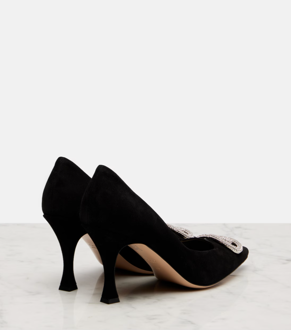 Black high-heeled shoes with decorative elements on a light background