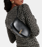 Person wearing a black polka dot dress with a black handbag featuring a gold logo.