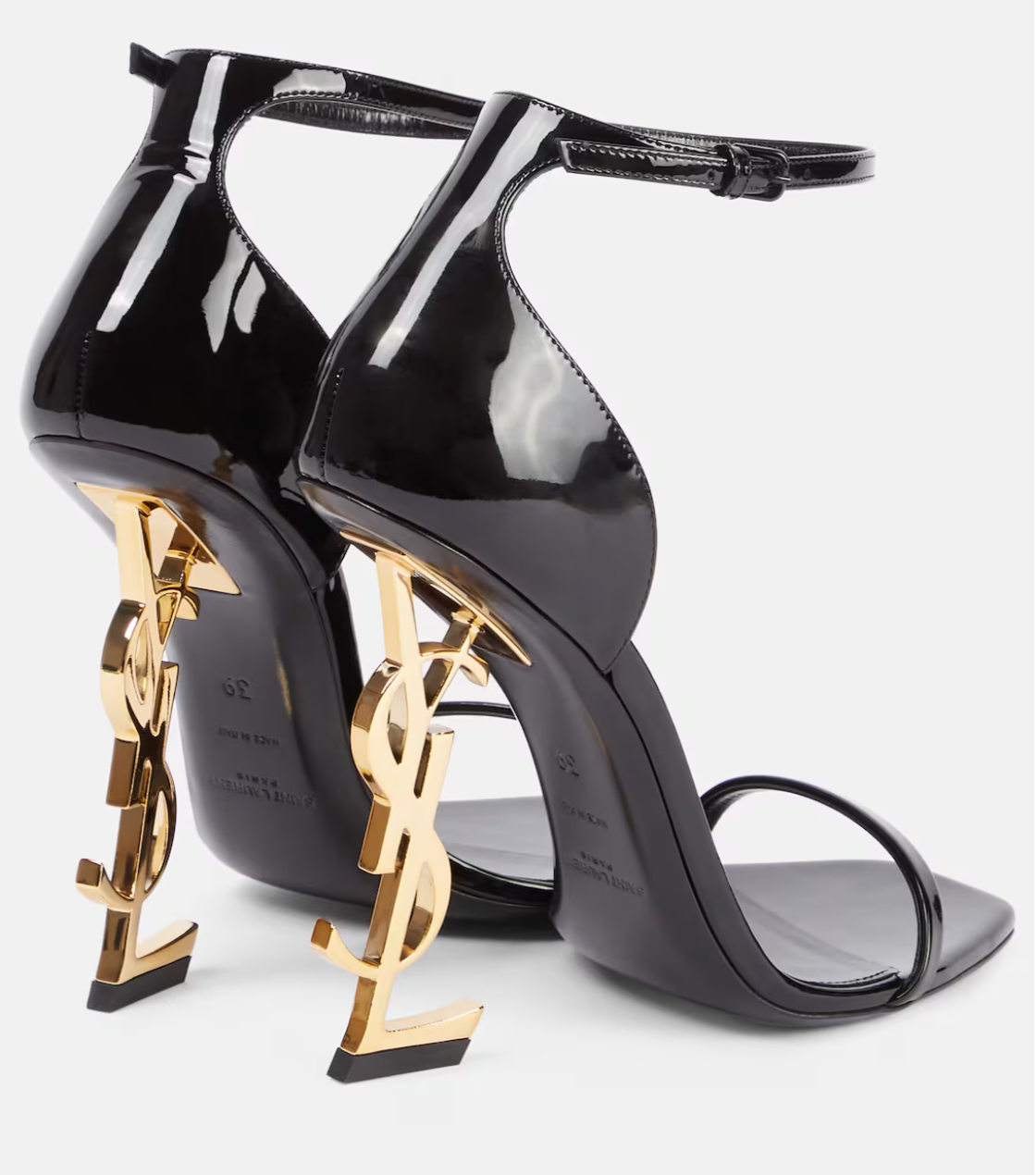 Black high-heeled shoes with gold YSL logo on a white background