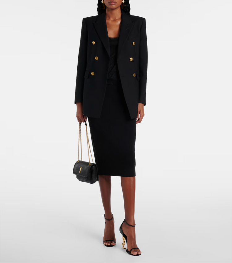 Person wearing a black double-breasted blazer and skirt set on a white background