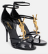 Black high-heeled sandals with gold logo on a white background