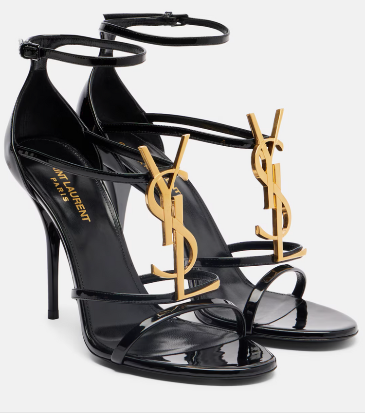 Black high-heeled sandals with gold logo on a white background
