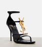 Black high-heeled sandal with gold logo on a white background