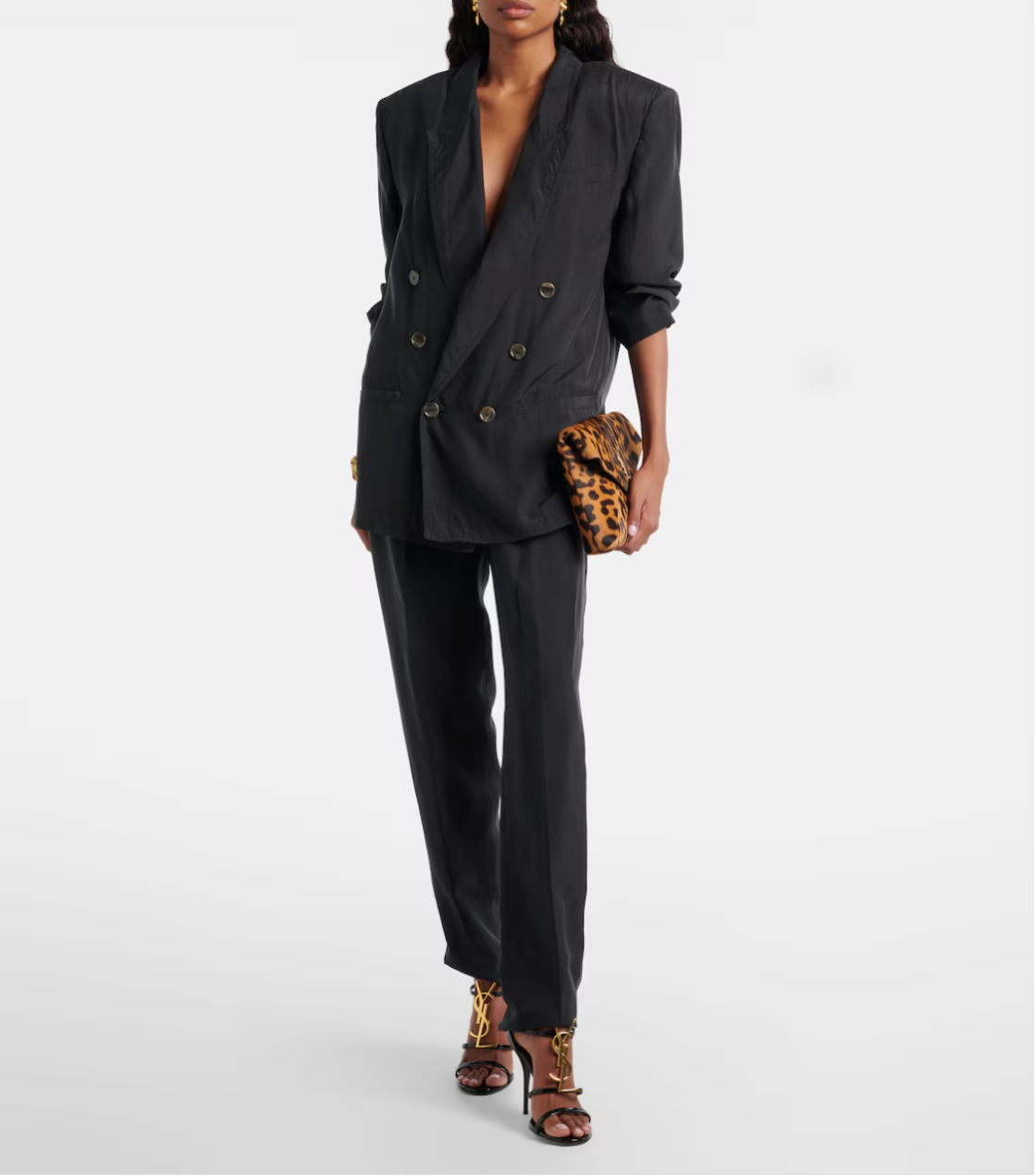 Person wearing a black suit with leopard print clutch on a white background