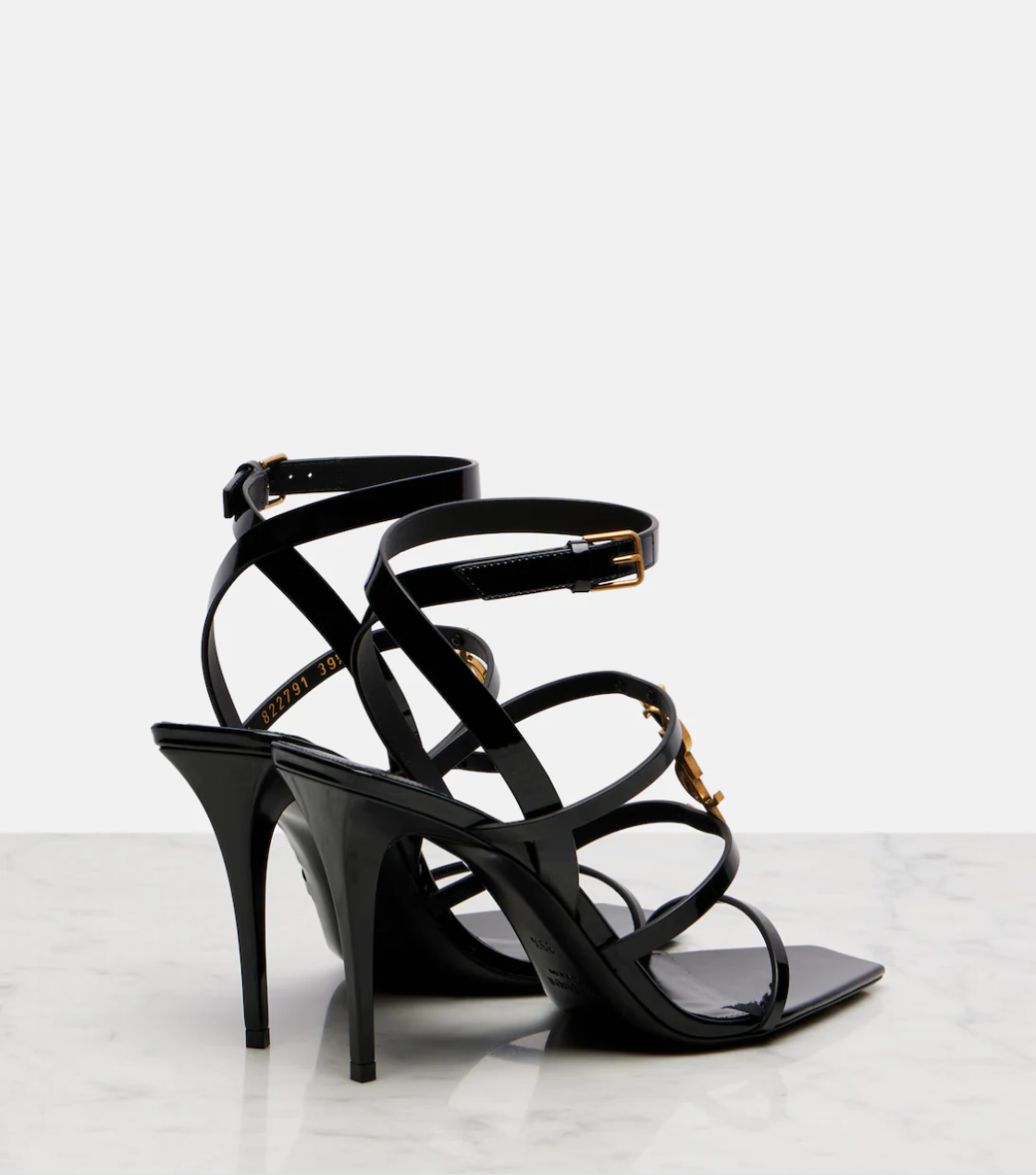 Black high-heeled sandals with strappy design on a light gray background