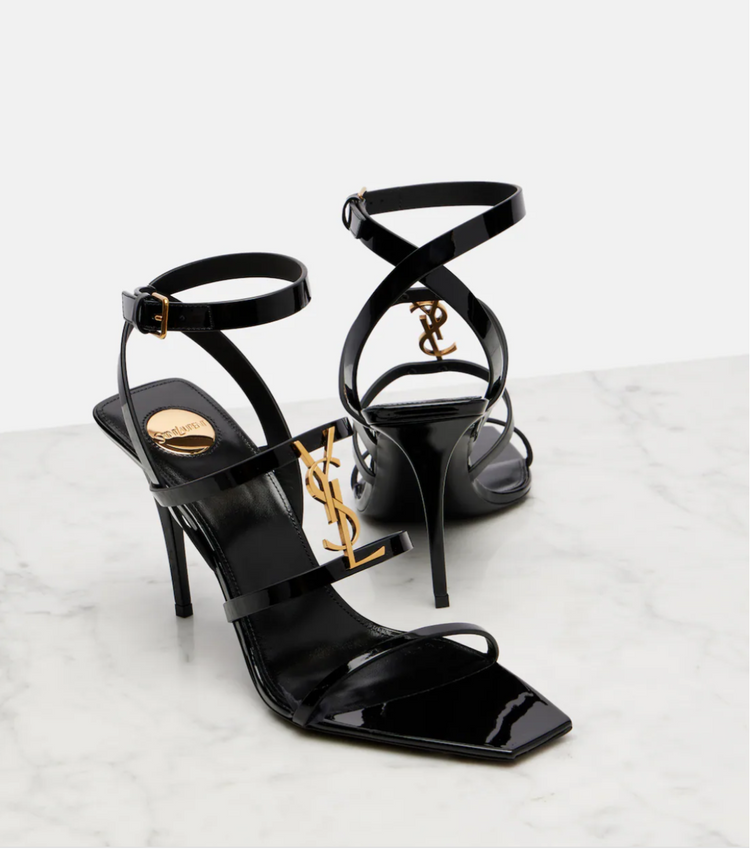 Black high-heeled sandals with criss-cross straps on a light gray background