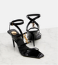 Black high-heeled sandals with criss-cross straps on a light gray background