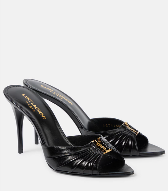 Black high-heeled sandals with gold accents on a white background