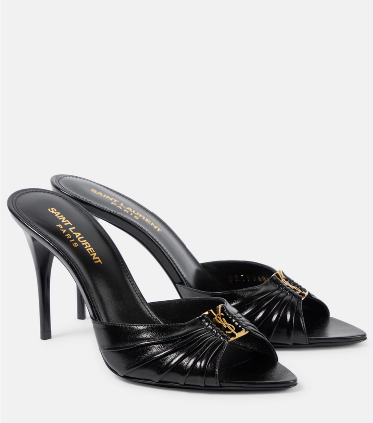 Black high-heeled sandals with gold accents on a white background