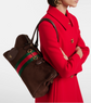 Person wearing a red coat with a brown Gucci bag featuring green and red stripes.