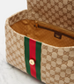 Designer handbag with monogram pattern and red and green stripe on a marble surface