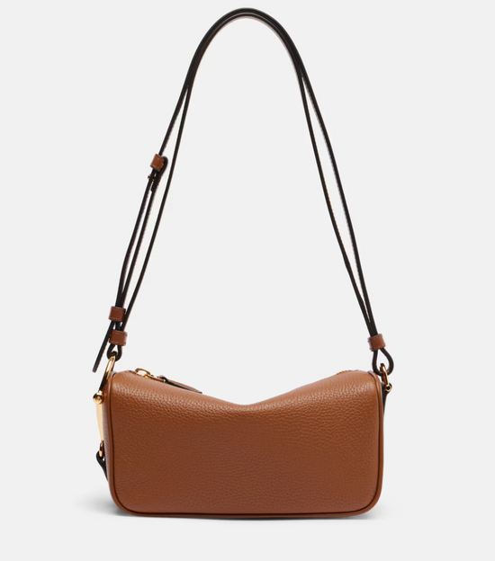 Brown leather handbag with a strap on a light gray background