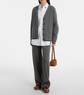 Person wearing a gray cardigan, white shirt, gray pants, and brown shoes on a white background