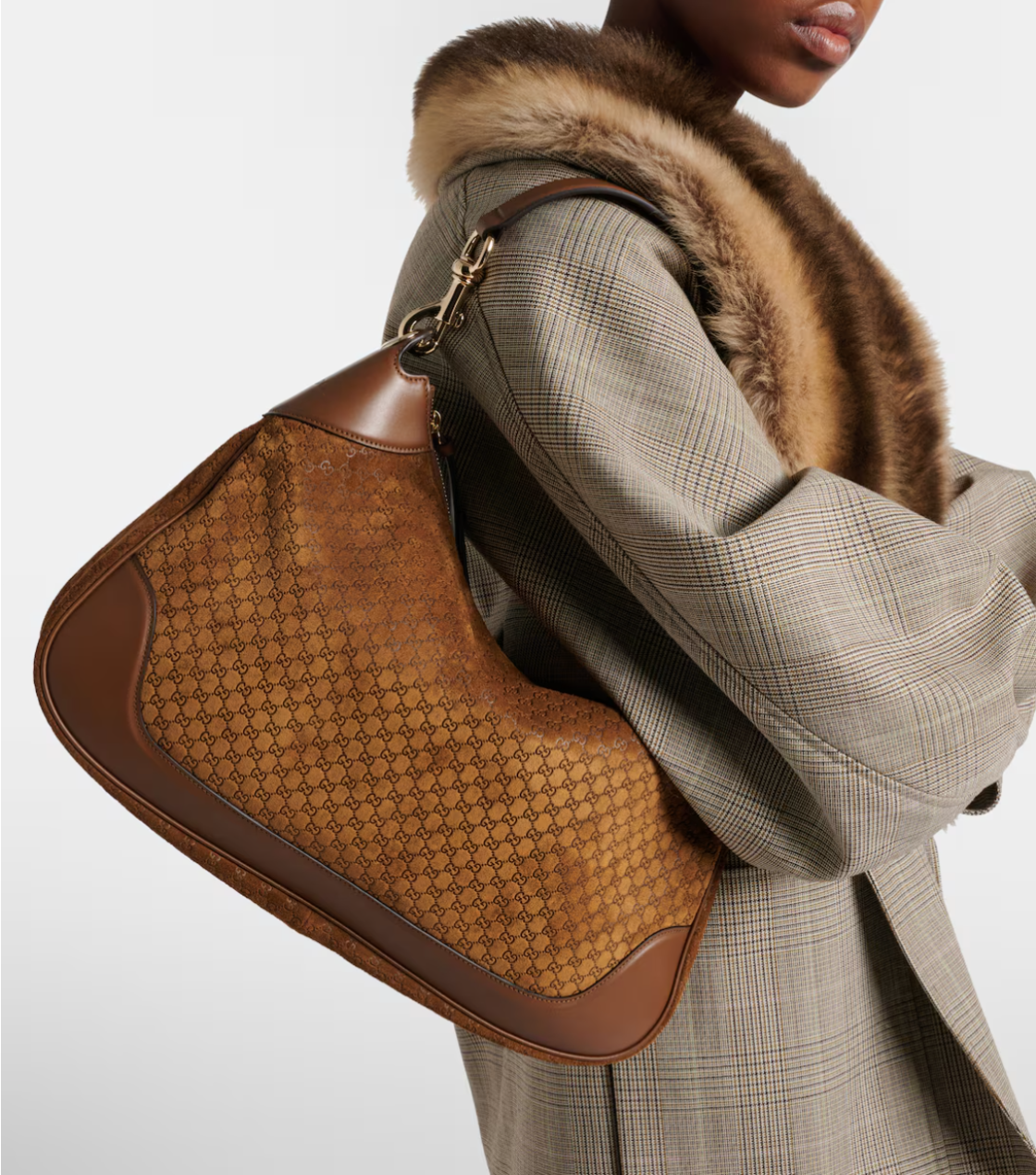 Brown textured handbag held by a person wearing a gray coat with fur collar.