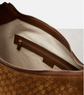 Close-up of a brown leather bag with a zipper, featuring the Gucci logo.