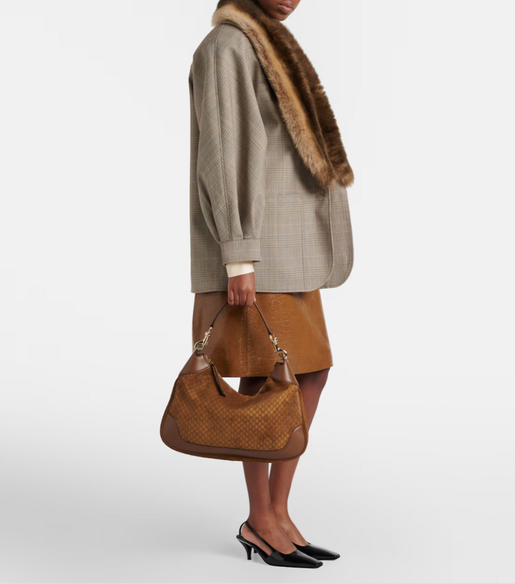 Person holding a brown handbag against a white background