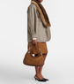 Person holding a brown handbag against a white background