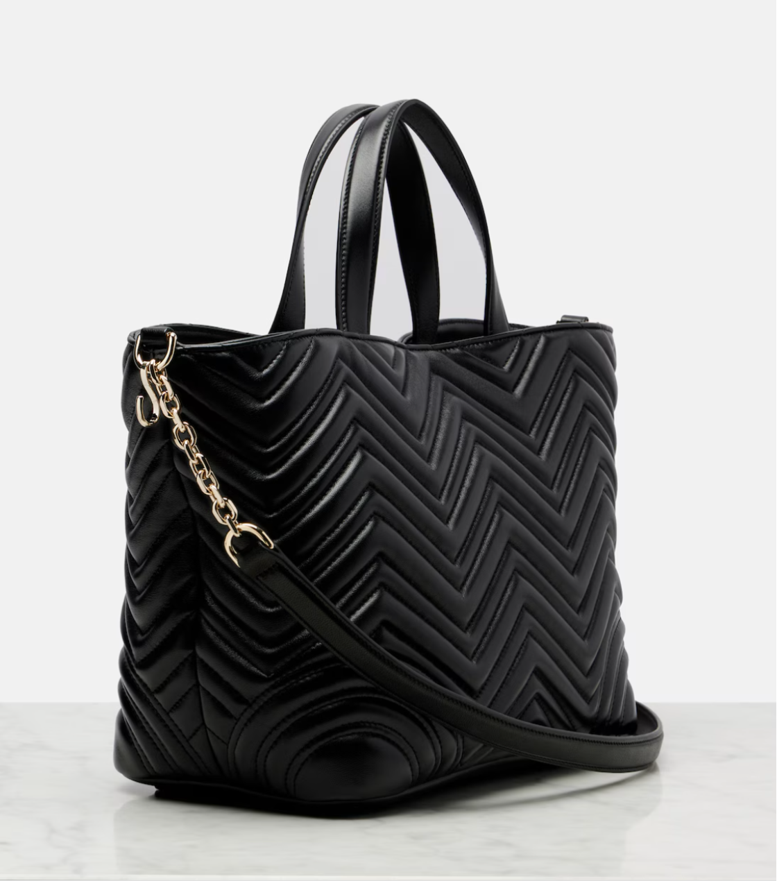 Black quilted handbag with a gold chain on a white background