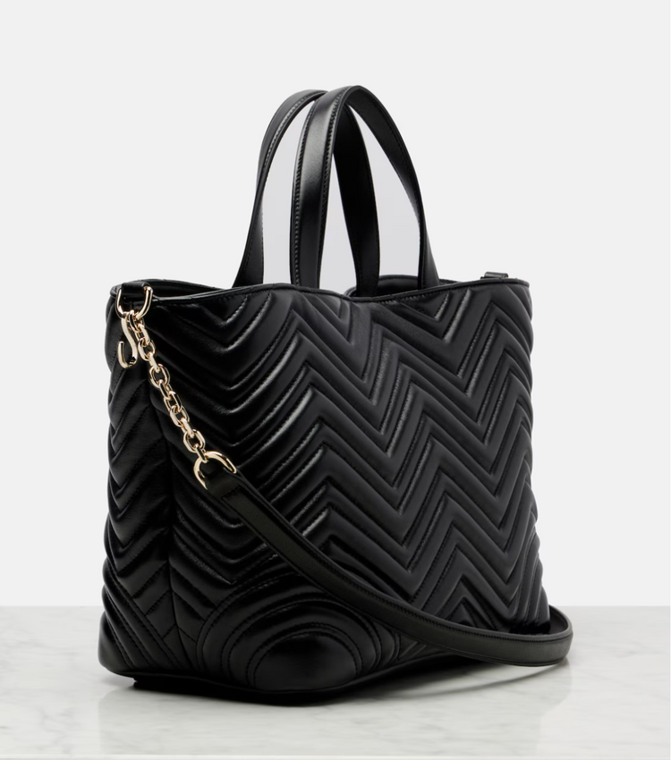 Black quilted handbag with a gold chain on a white background
