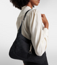 Person wearing a black shoulder bag on a plain background